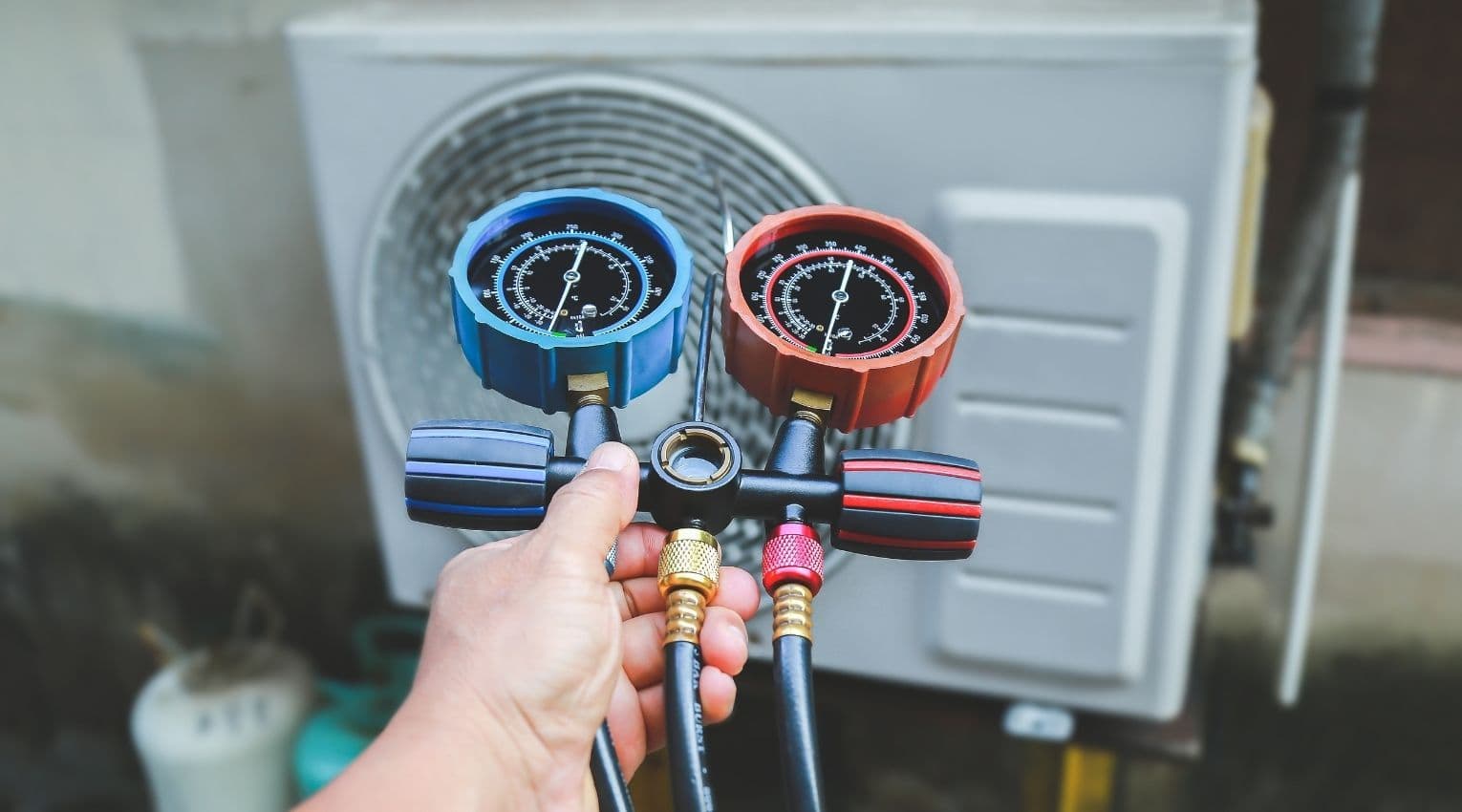 HVAC service technician uses gauges to check refrigerant